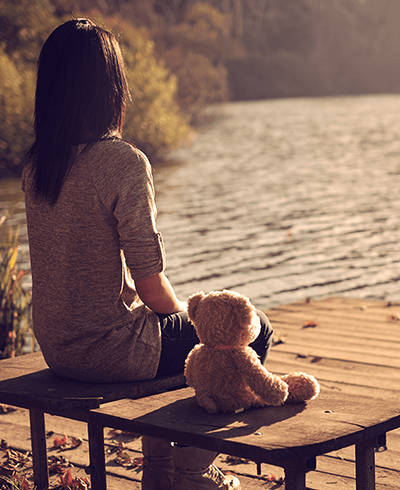 young childless woman on a bench with teddybear