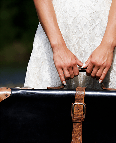 hands of a young woman clasping the handle of a suitcase
